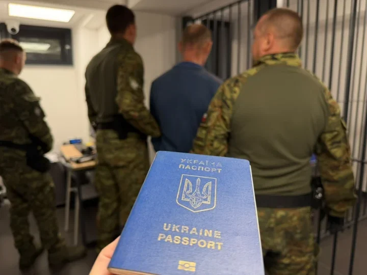 W ręku trzymany jest ukraiński paszport, a w tle funkcjonariusze w mundurach prowadzą mężczyznę w pomieszczeniu przypominającym areszt.
